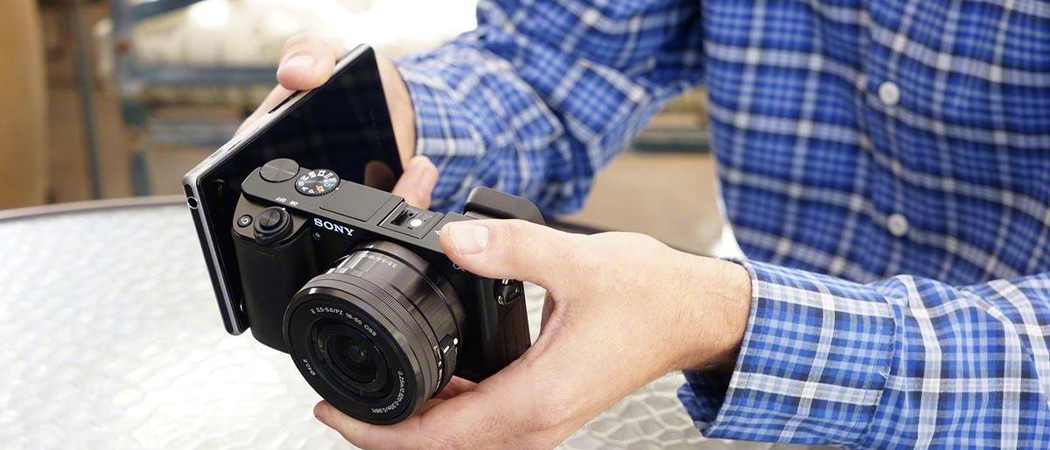 Een man die foto's overzet van een systeemcamera naar een smartphone.