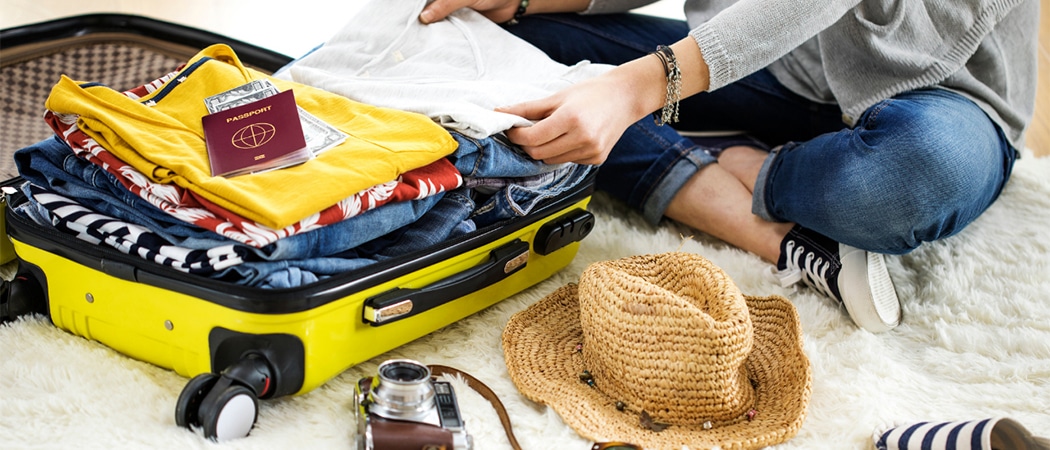 Een gevulde koffer met kleren, paspoort, hoed en fototoestel