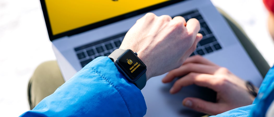 Een Apple Watch op de pols van een man met een computer op de achtergrond
