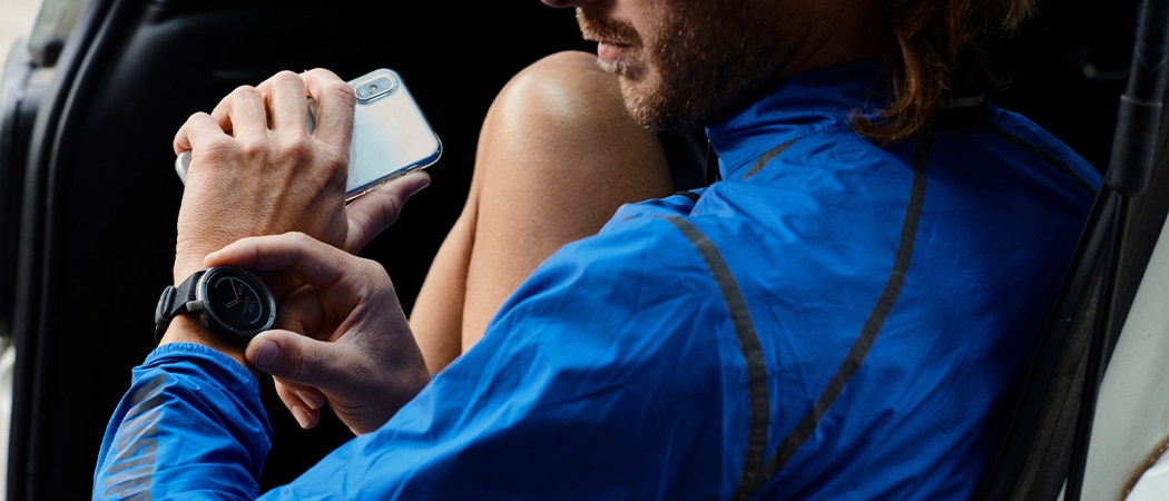 Man met een smartwatch aan de pols en een smartphone in de hand