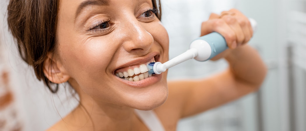 Een vrouw die haar tanden poetst met een elektrische tandenborstel