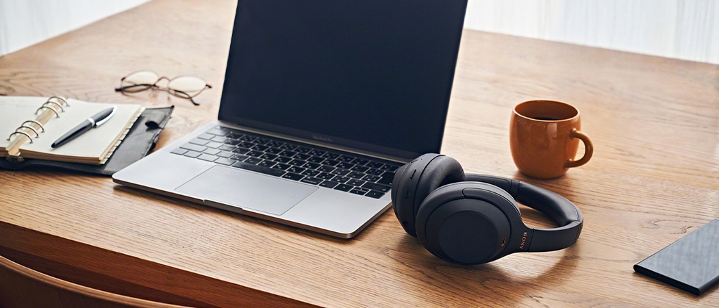 Een Sony draadloze koptelefoon op een bureau naast een MacBook.