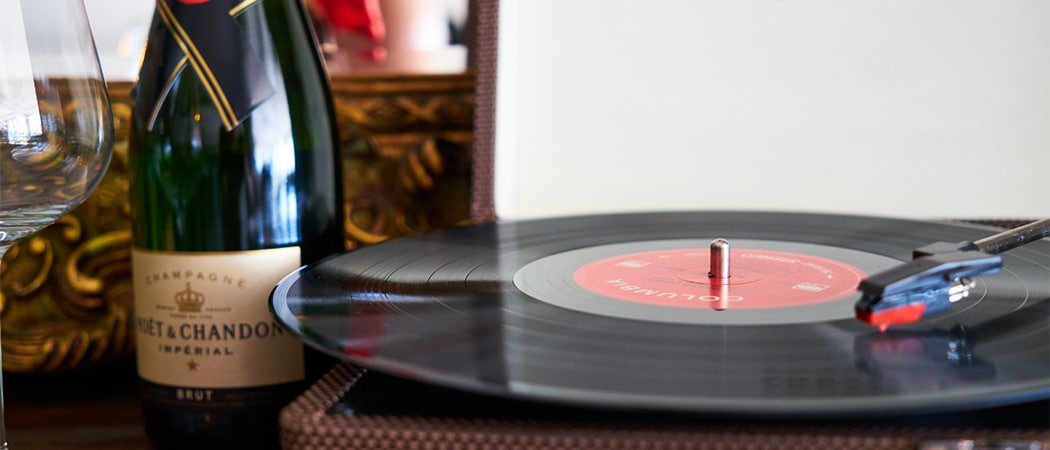 Een vinyl plaat op een platenspeler naast een fles champagne