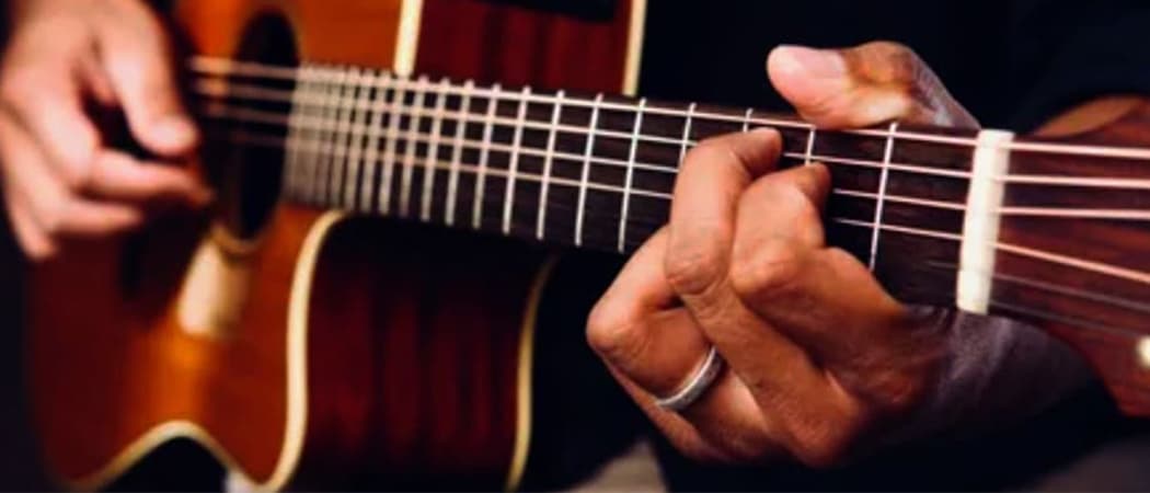 Close up van een man die akoestische gitaar speelt.