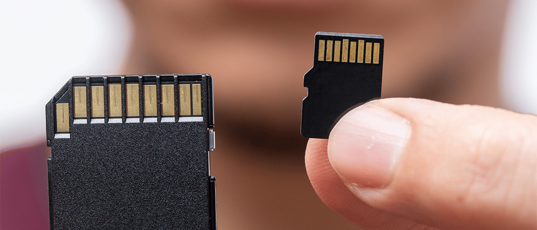 Een micro SD-kaart die wordt vastgehouden tussen twee vingers naast een SD-adapter.