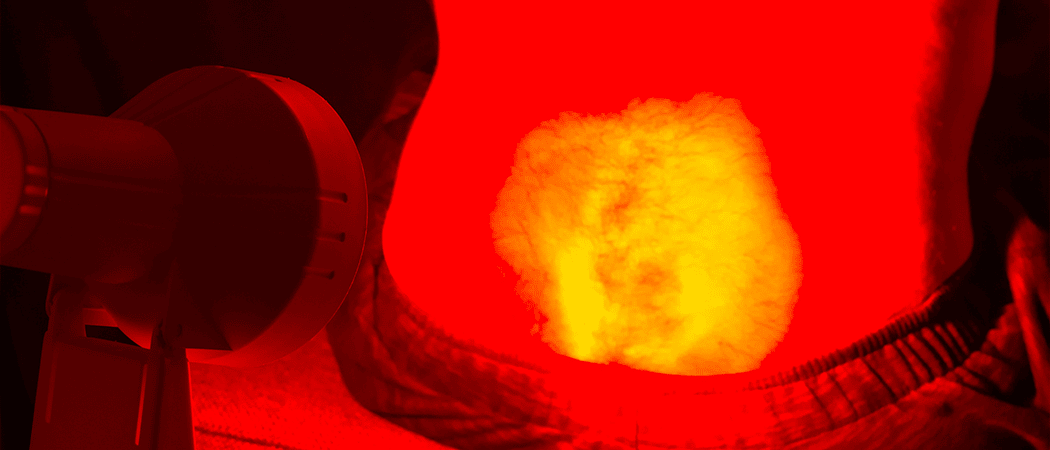 Een infraroodlamp gericht op iemand zijn onderrug.