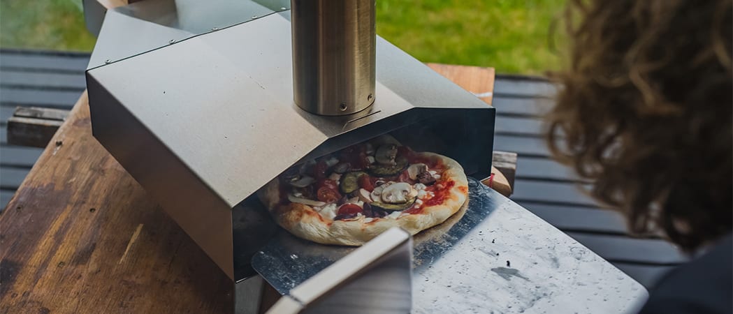 Een pizza die in een houtskool pizzaoven wordt geschoven.